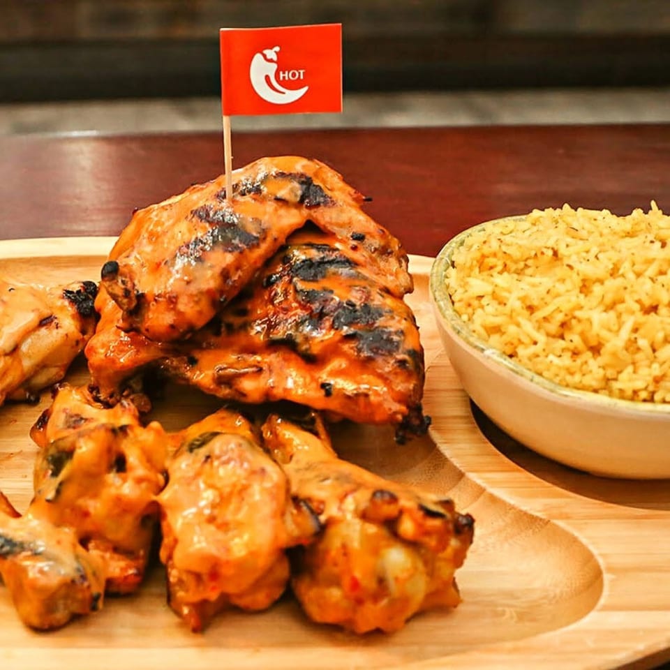 Grilled chicken wings with a "HOT" flag and a side of rice on a wooden platter.
